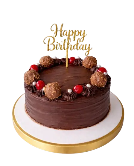 A round chocolate birthday cake decorated with Ferrero Rocher truffles, red cherries, and a gold 'Happy Birthday' topper."